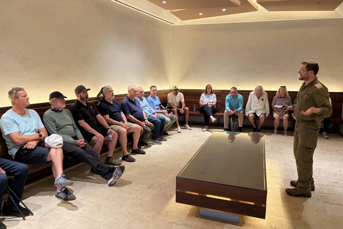 Mission participants seated around a room listen to a briefing by an IDF officer