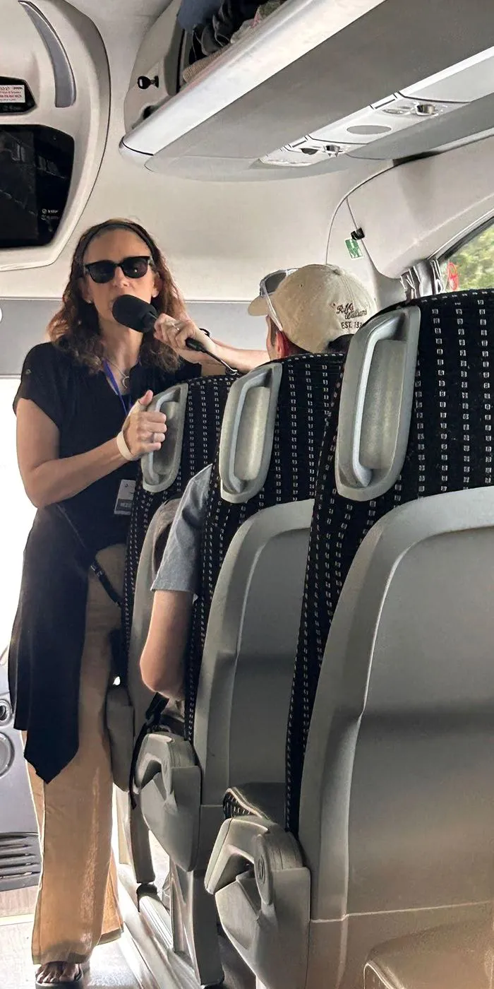A guide briefs participants on the bus